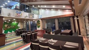 A multi-level restaurant with tiered seating, wooden ceiling beams, and a colorful striped floor. - HOTEL INDRALOK INN (Hazaribagh)