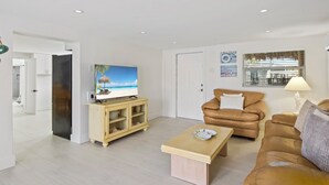 A modern living room with a television, leather sofa, and a wooden coffee table. - ☀️ Private Pool, Canal Front - Pet Friendly - The Nellie ☀️ (Fort Myers Beach)