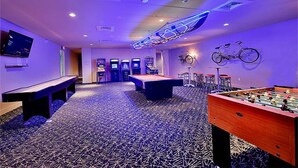 A room with a pool table, foosball table, and a bar area with stools. - The Cozy Corner | Dual Beach & Pool Views (Galveston)