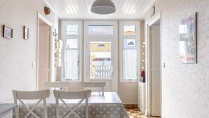 Ruokailutila, jossa on pöytä ja tuolit, kattovalaisin ja näkymä ikkunoista.