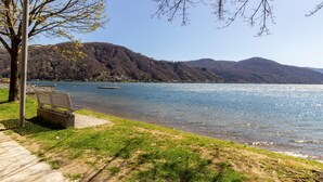 Un parc au bord du lac, avec un banc, un lampadaire et une vue dégagée sur le lac et les montagnes.
