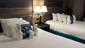 A hotel room with two beds, a nightstand with a lamp, a ceiling fan, and a large window with curtains. - Stylish ocean view 2 queen efficiency condo in marvelous Myrtle Beach (Myrtle Beach)