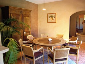 A dining area with a round wooden table surrounded by wicker chairs, a wooden cabinet, and a framed botanical illustration on the wall. - Dolce Vita (Mondragon)