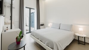 Una habitación de hotel moderna con cama, mesita de noche, lámpara, planta en maceta y un ventanal grande.