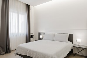 A hotel room with a bed, bedside tables, a lamp, and a window with curtains.