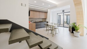 A modern kitchen with wooden cabinets, a dining area with a table and chairs, and a staircase leading to another level. - Room 'Casa Umeli Giarraffa' with Shared Terrace, Wi-Fi and Air Conditioning (Marsala)