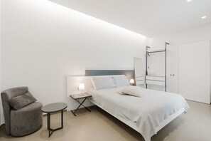 A modern bedroom with a bed, bedside tables, a chair, and a wardrobe. - Room 'Casa Umeli Nocellara' with Shared Terrace, Wi-Fi and Air Conditioning (Marsala)