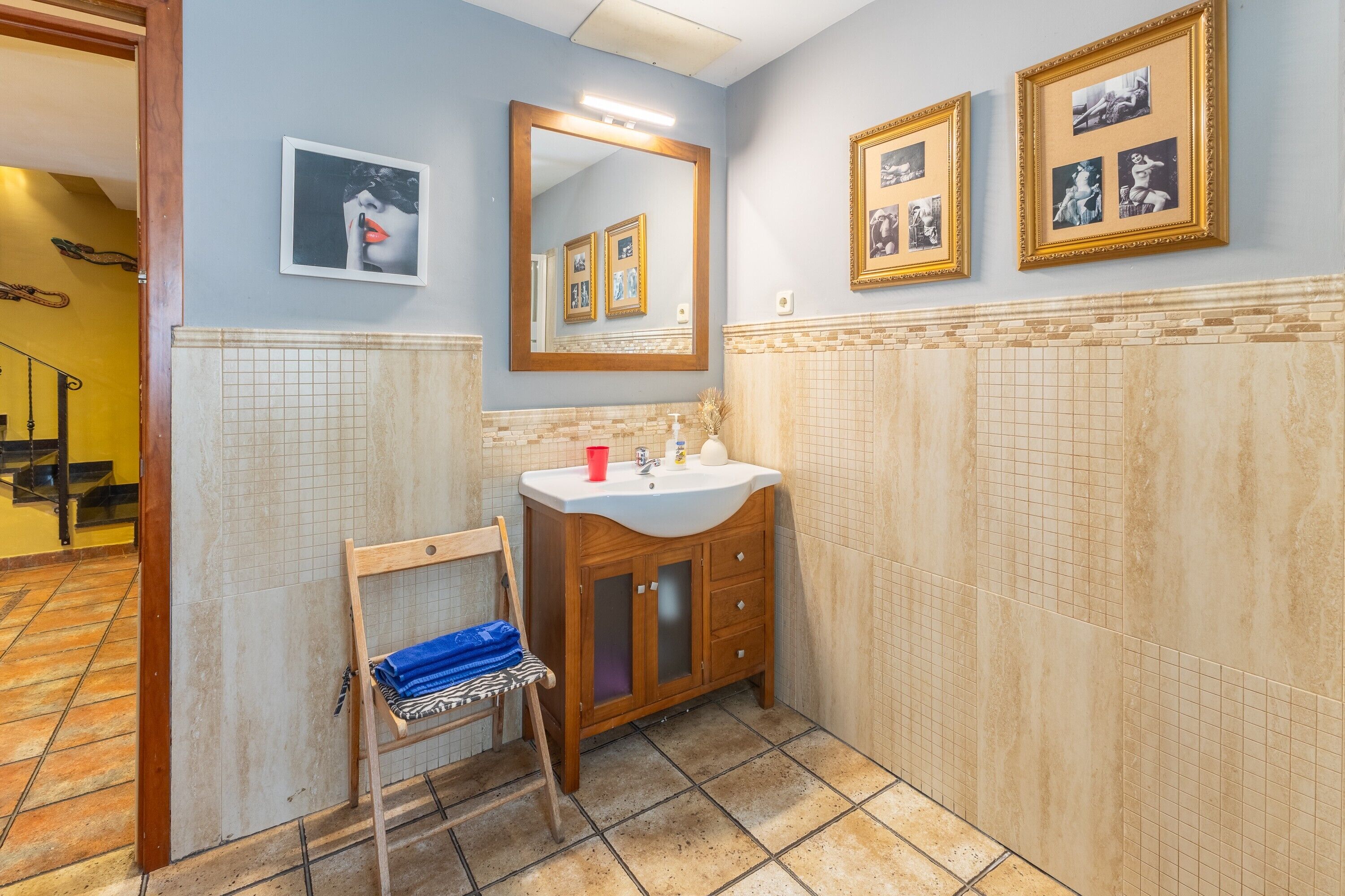 A bathroom with a wooden vanity, a mirror, and tiled walls.
