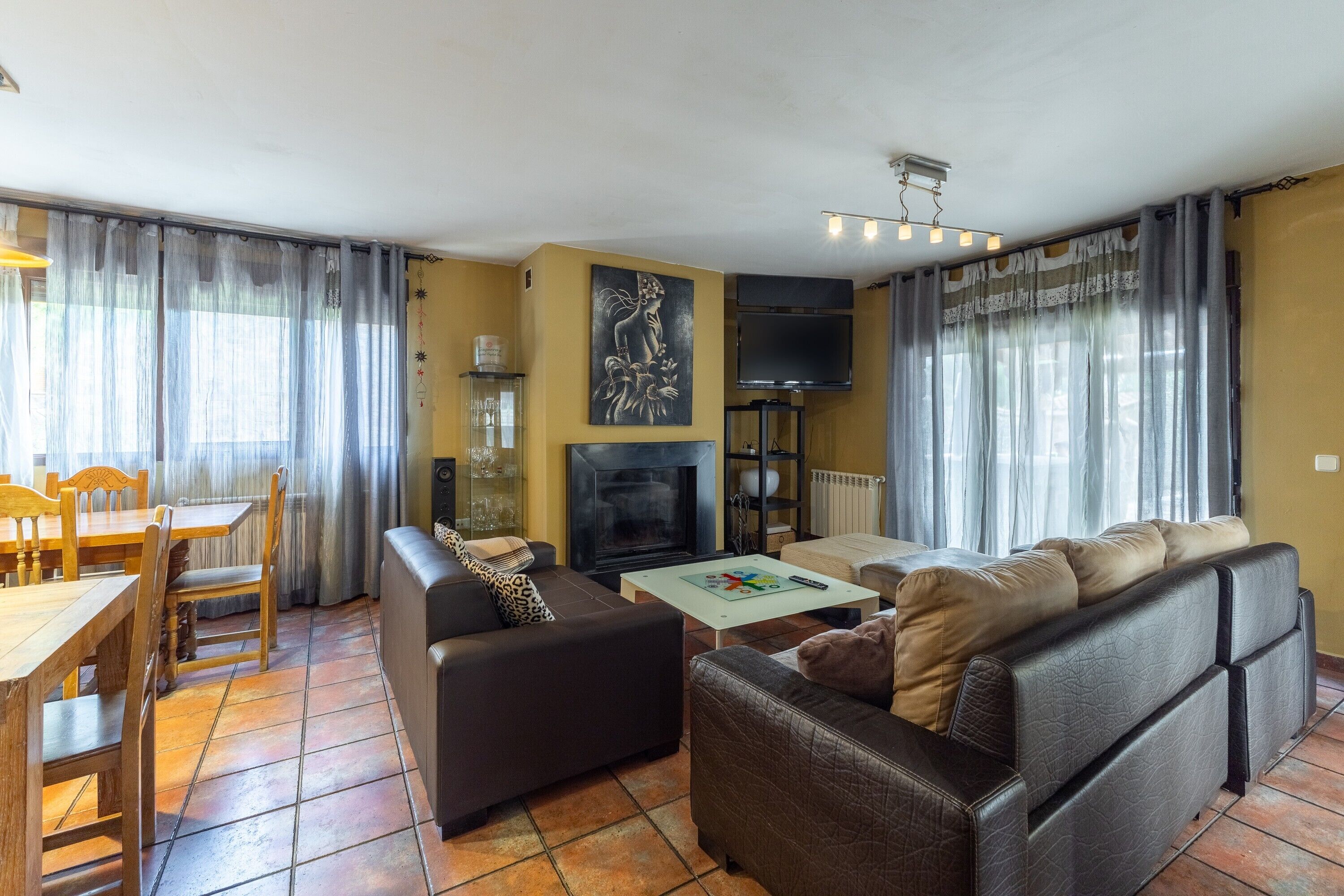 A living room with a sofa, a coffee table, a fireplace, a TV, and a dining area with chairs and a table.