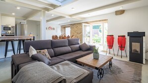 Un salon moderne avec un canapé d’angle, une table basse en bois et un mur en pierre.