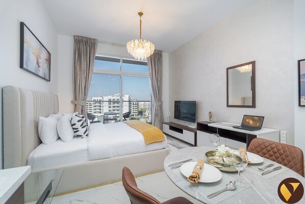 Una moderna camera d'hotel con un letto, una scrivania, un tavolo da pranzo per due e un'ampia finestra con vista sulla città.