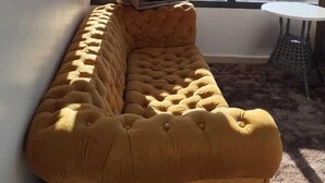 Ein Zimmer mit einem großen Fenster, einem geschnörkelten Sofa und einem kleinen runden Tisch.