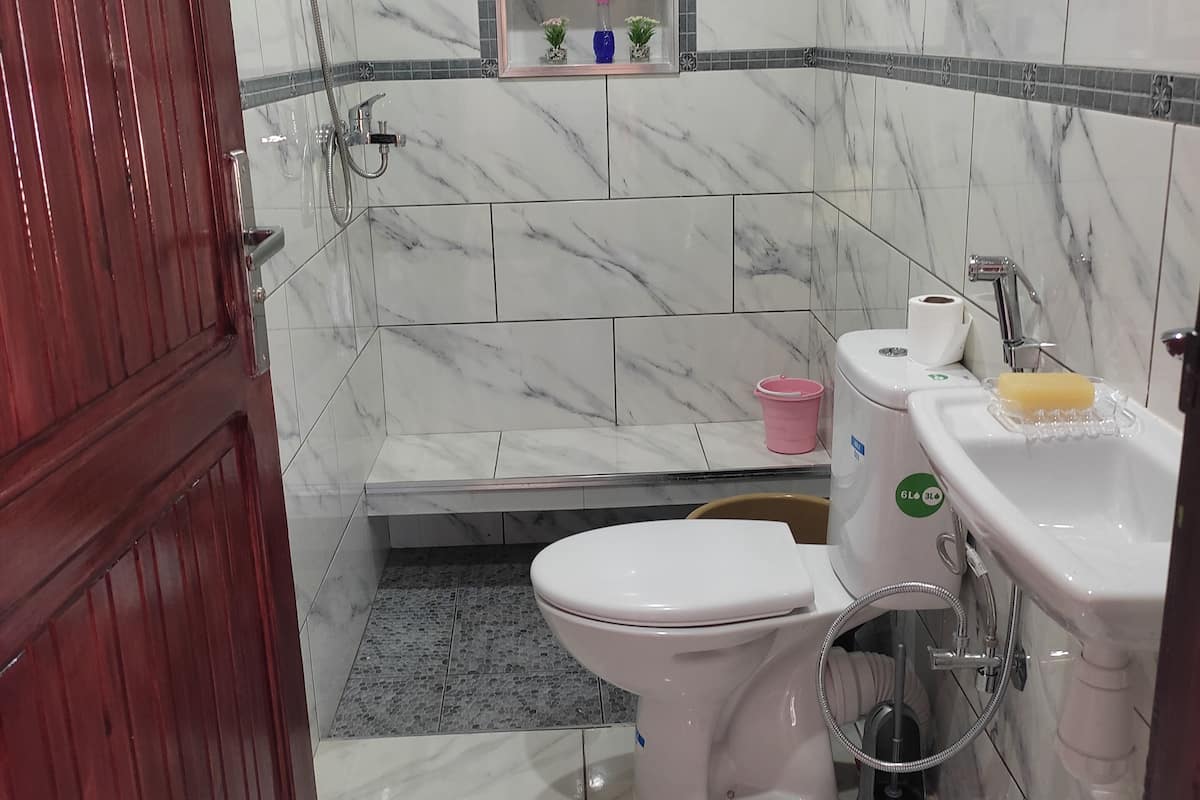 Et badeværelse med toilet, vask og brusebad.