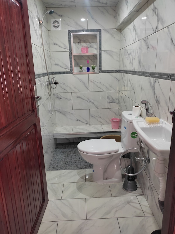Un baño con inodoro, lavabo y ducha.