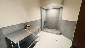 Un baño pequeño con ducha, un banco y un perchero.