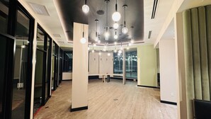 Una oficina amplia y moderna con suelo de madera, ventanas grandes y lámparas colgantes.
