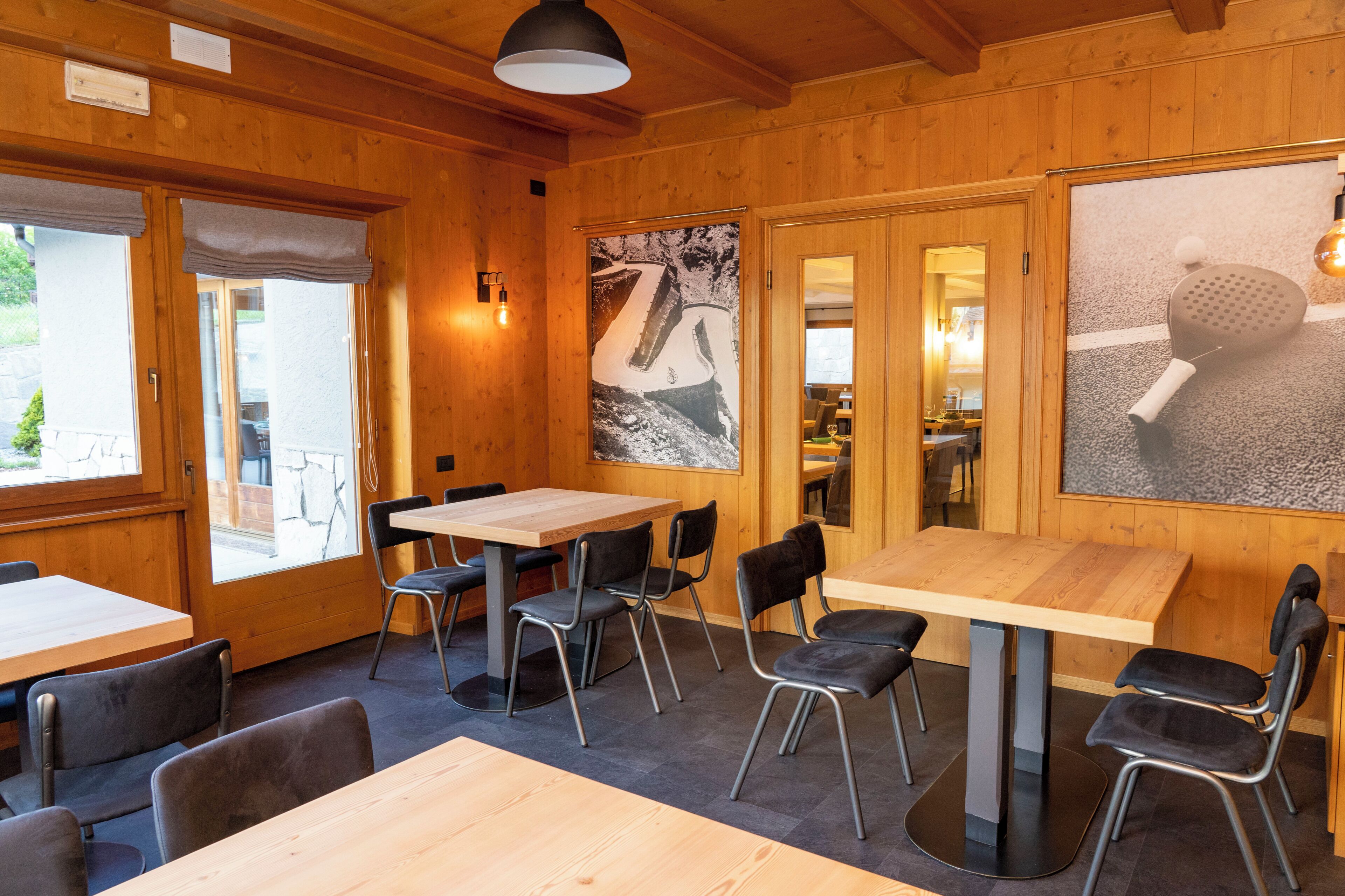 A wooden interior with tables and chairs, a large poster, and a door leading to another room.