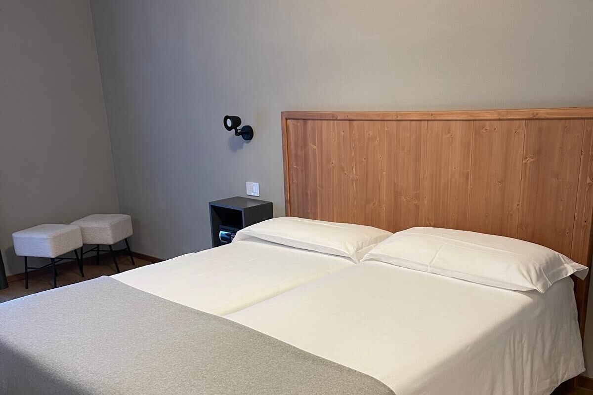 A bedroom with a large bed, a wooden headboard, a bedside table, and a small seating area with two chairs.