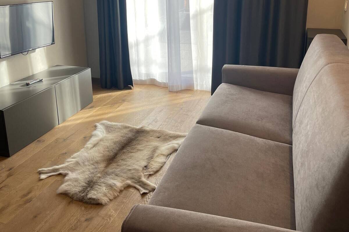 A modern living room with a sofa, a television, and a fur rug on the floor.