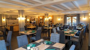 A restaurant with multiple dining tables, chairs, and a bar area. - Condhotel Fanti Ski & Bike (Valdisotto)