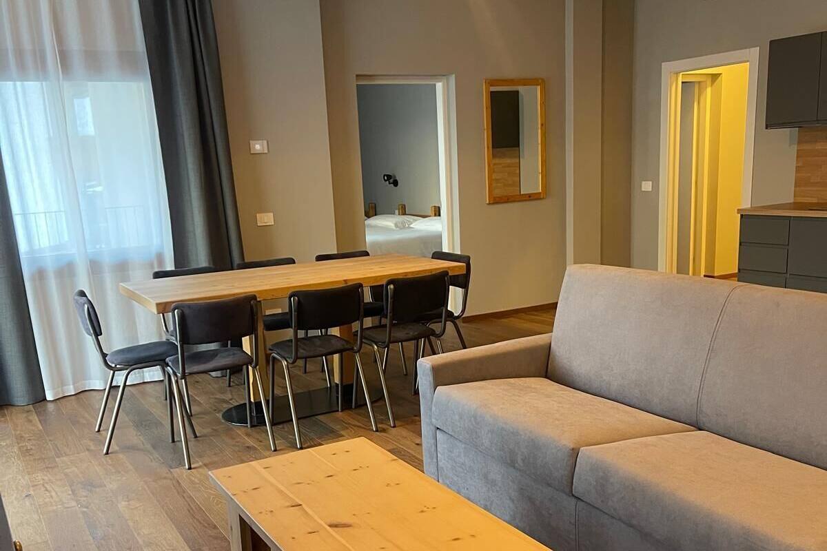 A modern living room with a sofa, a wooden coffee table, and a dining area with a table and chairs.