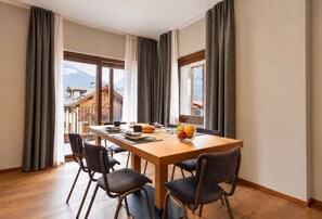 Un coin repas avec une table en bois, quatre chaises et un saladier rempli de fruits.