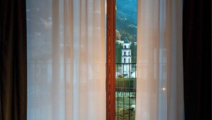A room with a view of a mountain and a church through sheer curtains. - Condhotel Fanti Ski & Bike (Valdisotto)