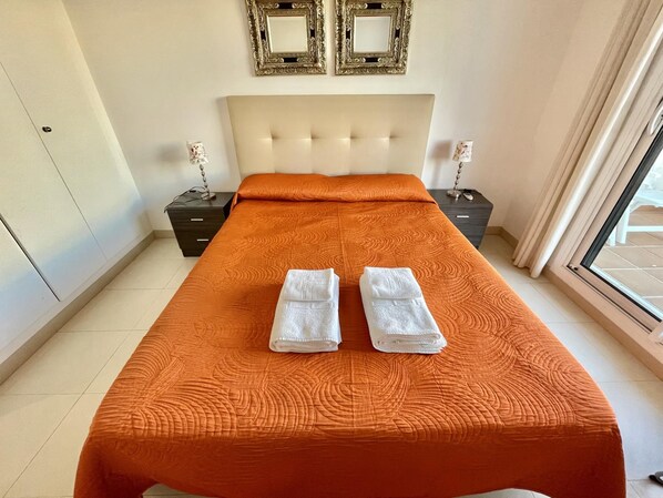 A hotel room with a large bed, two nightstands, a headboard, and two wall-mounted picture frames.