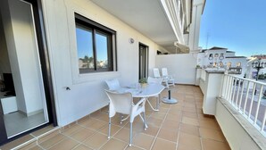 A balcony with a dining table and chairs, a small kitchen area, and a view of the cityscape. - Central apartment next to the Balcón de Europa (Nerja)