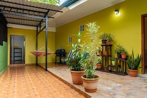 Un patio couvert aménagé avec un hamac, des plantes en pot et un petit coin salon extérieur.
