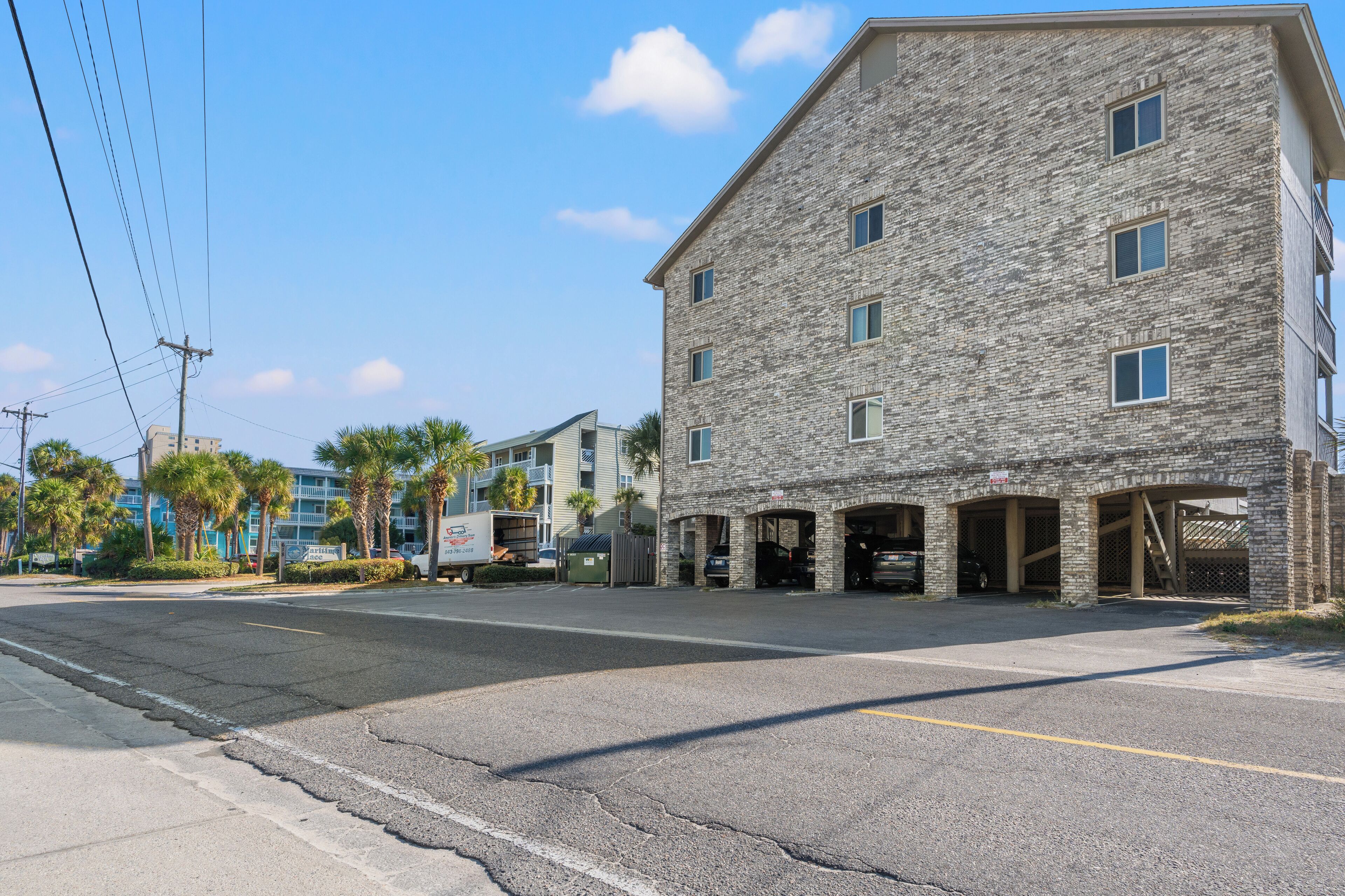 A multi-story building with a stone facade, multiple garage entrances, and a parking lot.