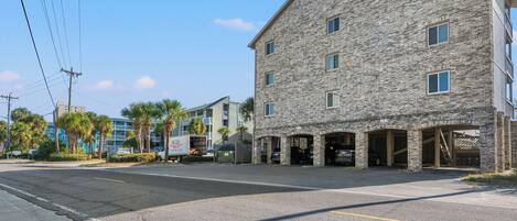 A multi-story building with a stone facade, multiple garage entrances, and a parking lot.
