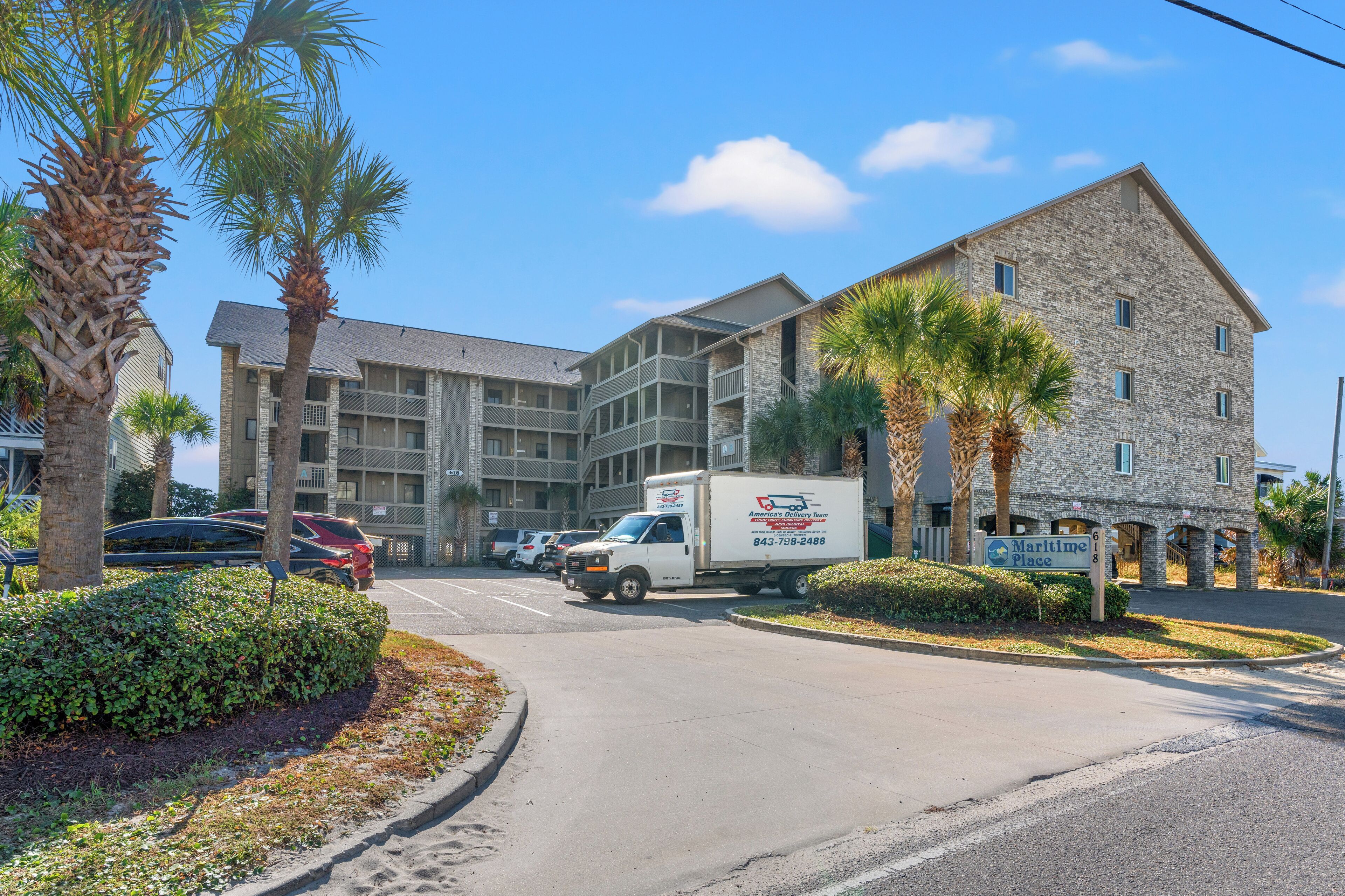 A multi-story building with a stone facade, a parking lot, and a sign for 'Maritime Place'.
