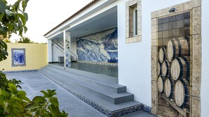 A building with a tiled exterior, a staircase leading to a covered area, and a door with barrel designs.