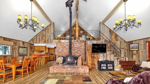Un interior rústico con chimenea de ladrillo, pisos de madera, una zona de comedor y un rincón de estar acogedor.