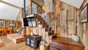 Un interior rústico con una escalera de madera, una chimenea y un televisor.
