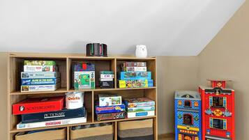 A room with a wooden bookshelf filled with various board games and puzzles.