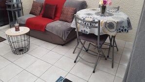 A cozy outdoor seating area with a sofa, a small round table, and a chair. - Coraux Residence house+Veranda park piscines (Canet-en-Roussillon)