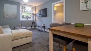 Una sala moderna con un sofá, una mesa de centro, una mesa de comedor y un televisor montado en la pared.