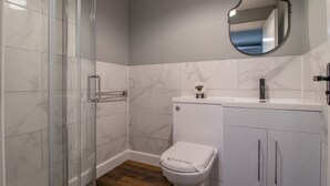 Un baño con cabina de ducha de vidrio, inodoro, lavabo y espejo.