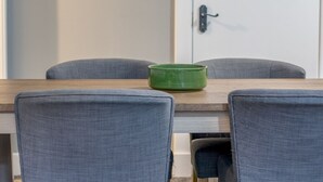 Una mesa de comedor con sillas, un cuenco verde y una puerta con manija.