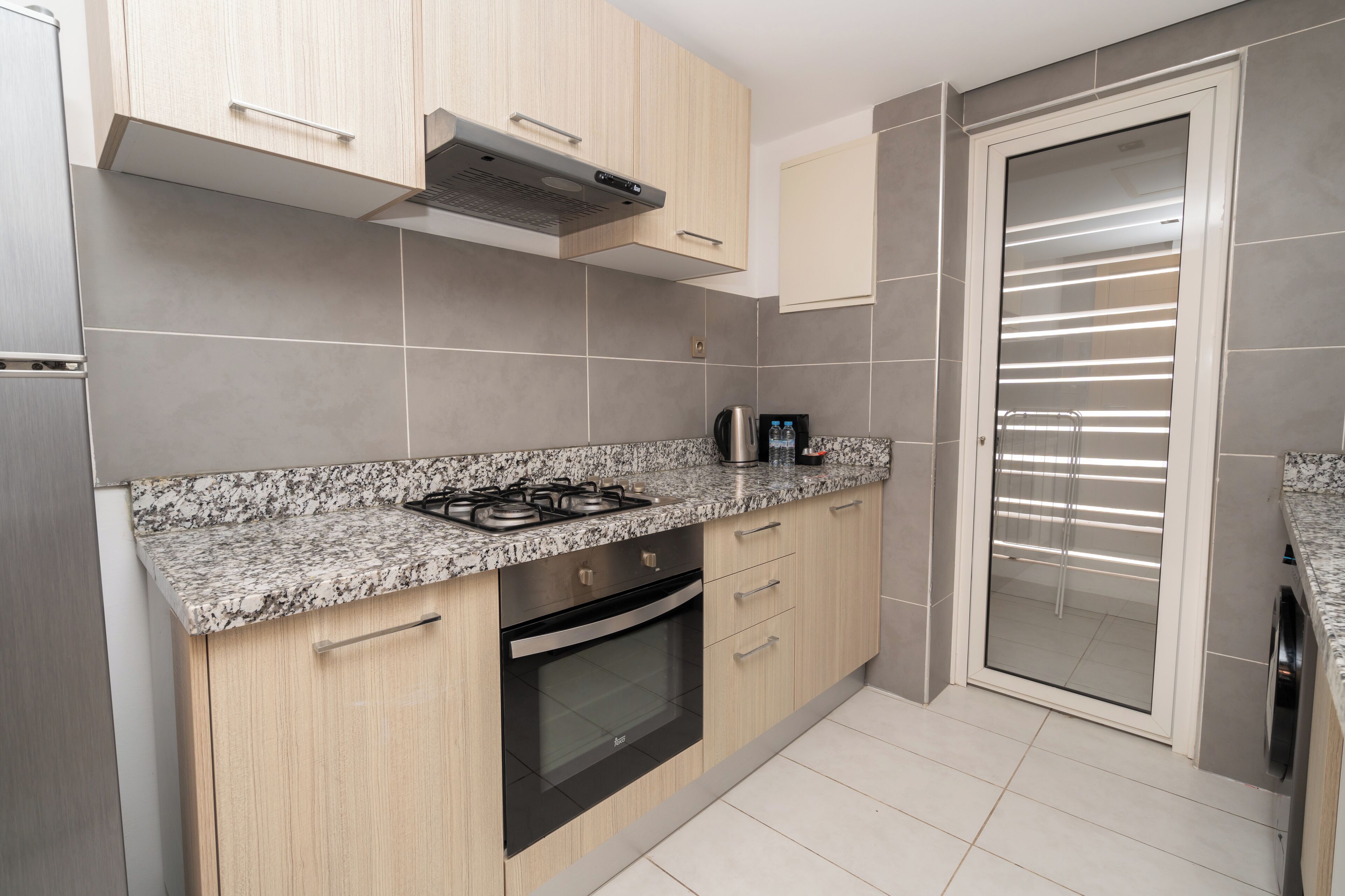 A modern kitchen with granite countertops, stainless steel appliances, and light wood cabinetry.