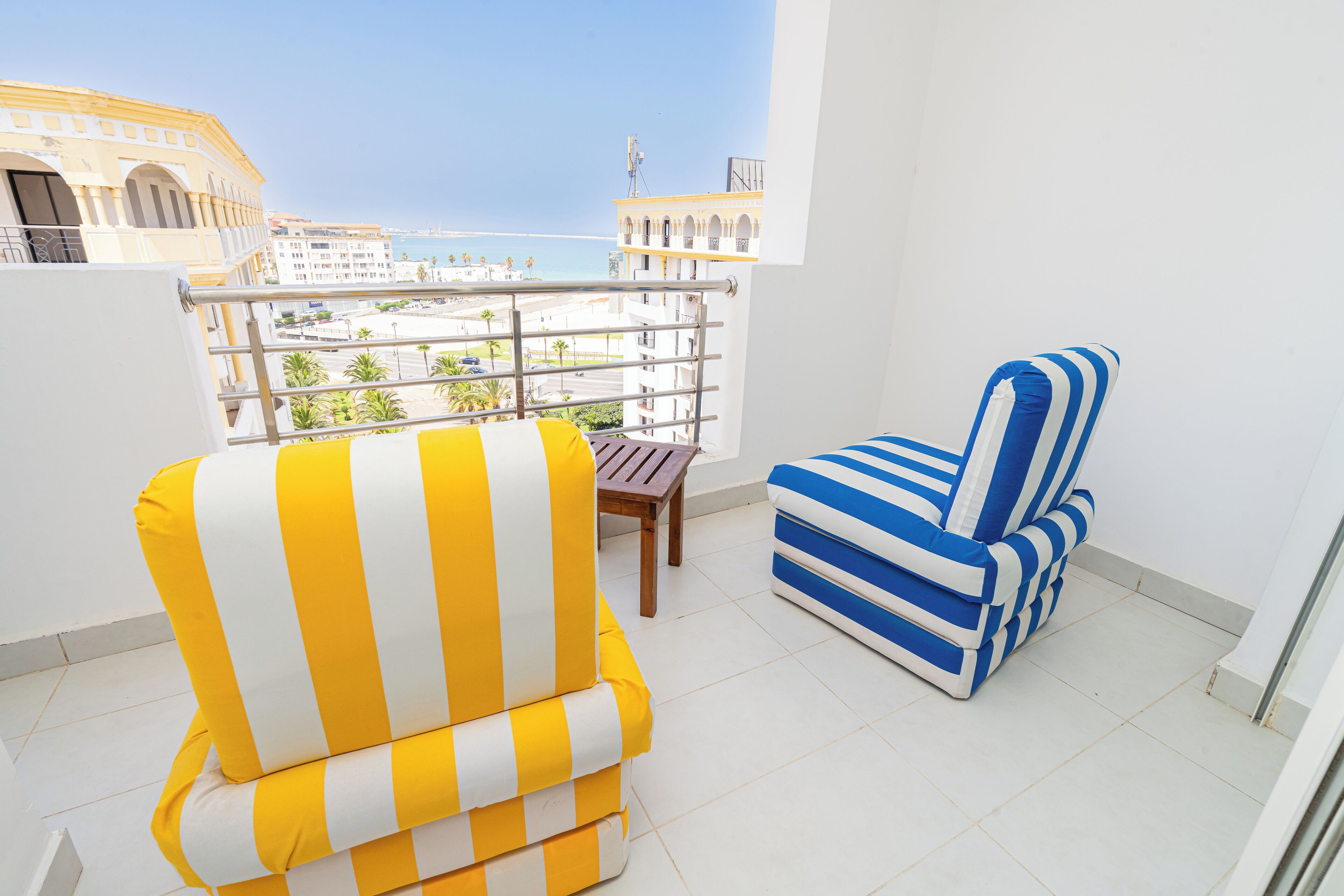 Un balcón con un sillón amarillo y blanco a rayas y un sofá azul y blanco a rayas.