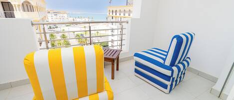 Un balcón con un sillón amarillo y blanco a rayas y un sofá azul y blanco a rayas.