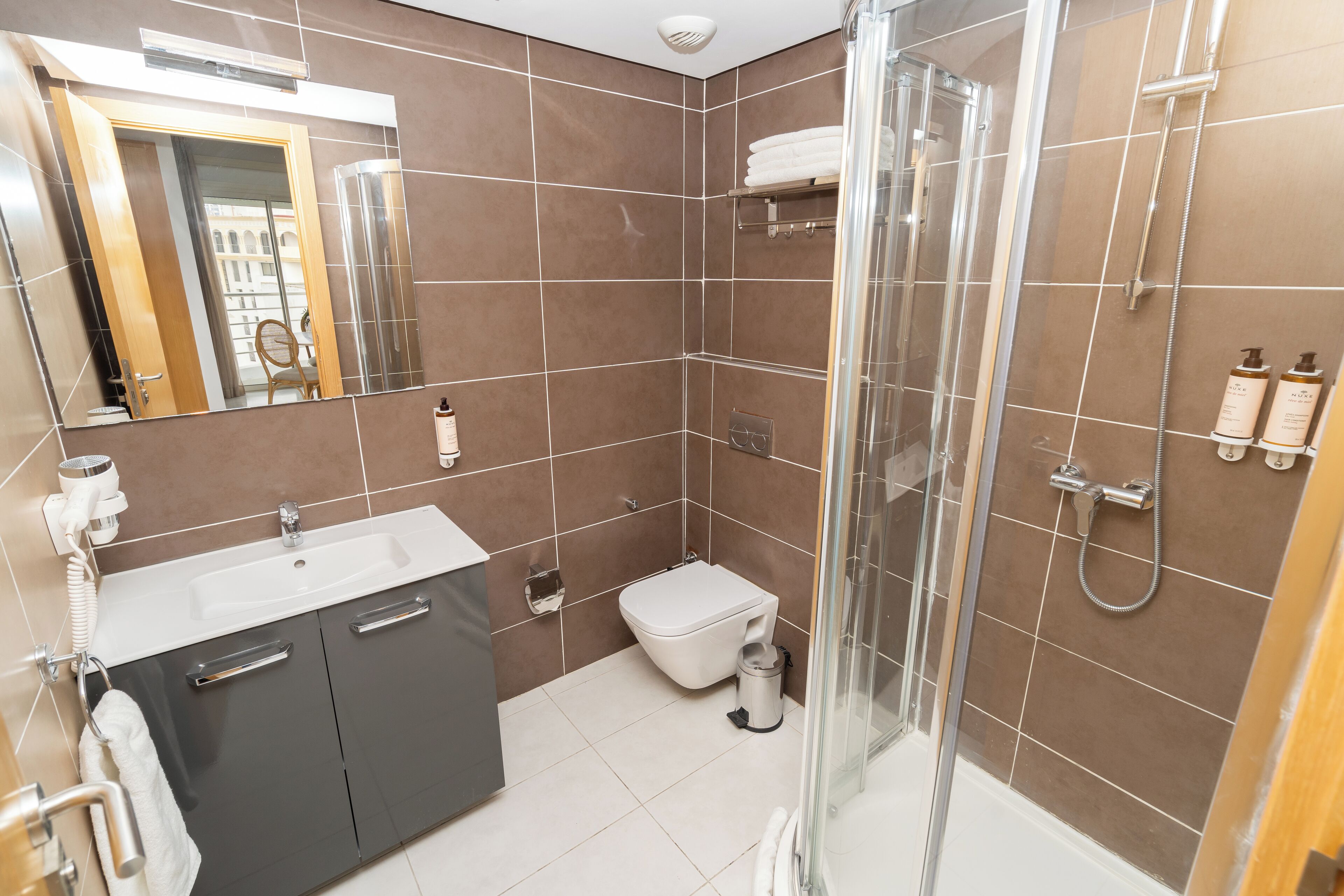 A modern bathroom with a glass-enclosed shower, a white sink, and a toilet.