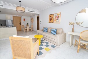 Una sala de estar moderna con un sofá, sillas, una mesa de comedor y una cocina al fondo.