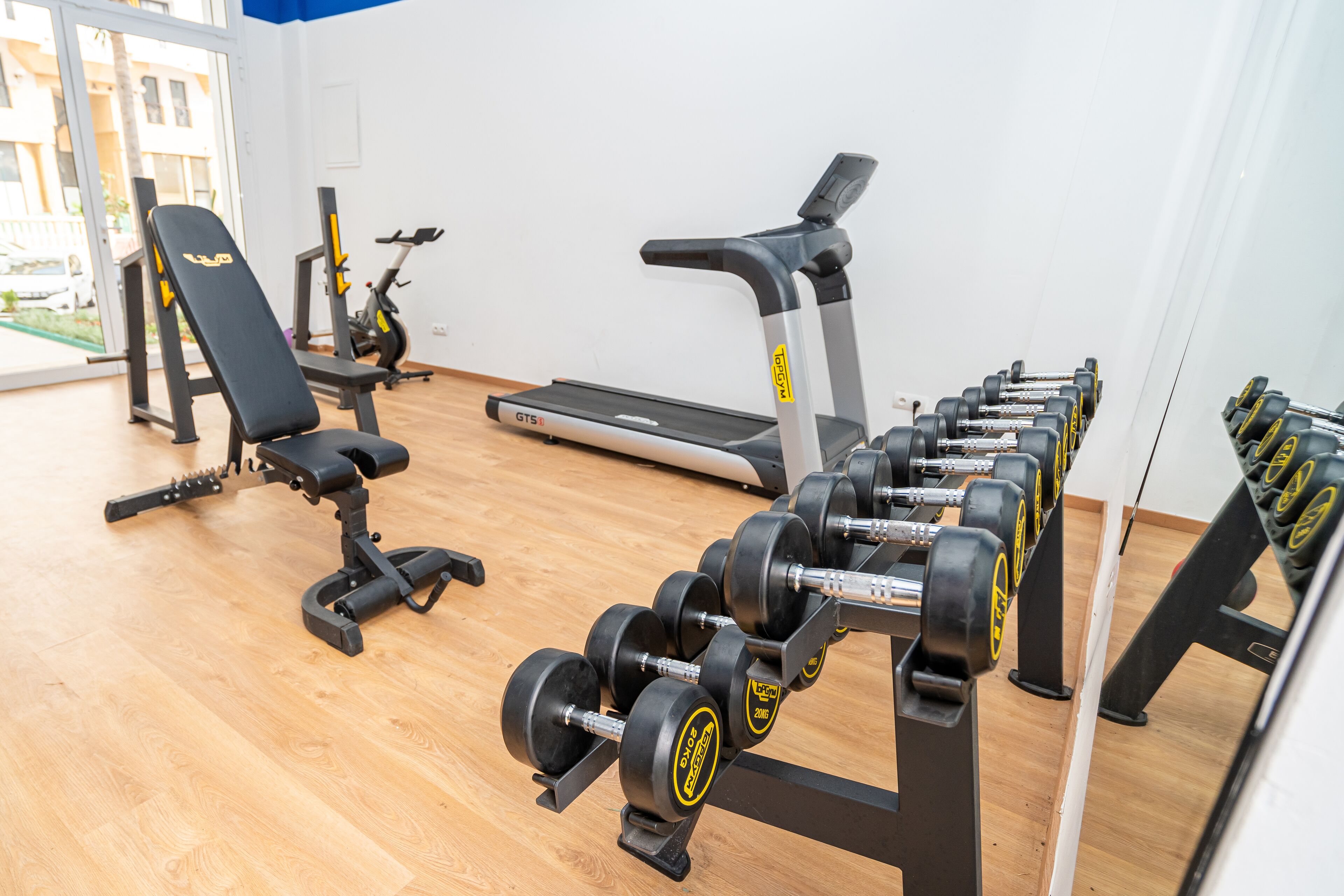 A gym with exercise equipment including dumbbells, a bench, and a treadmill.