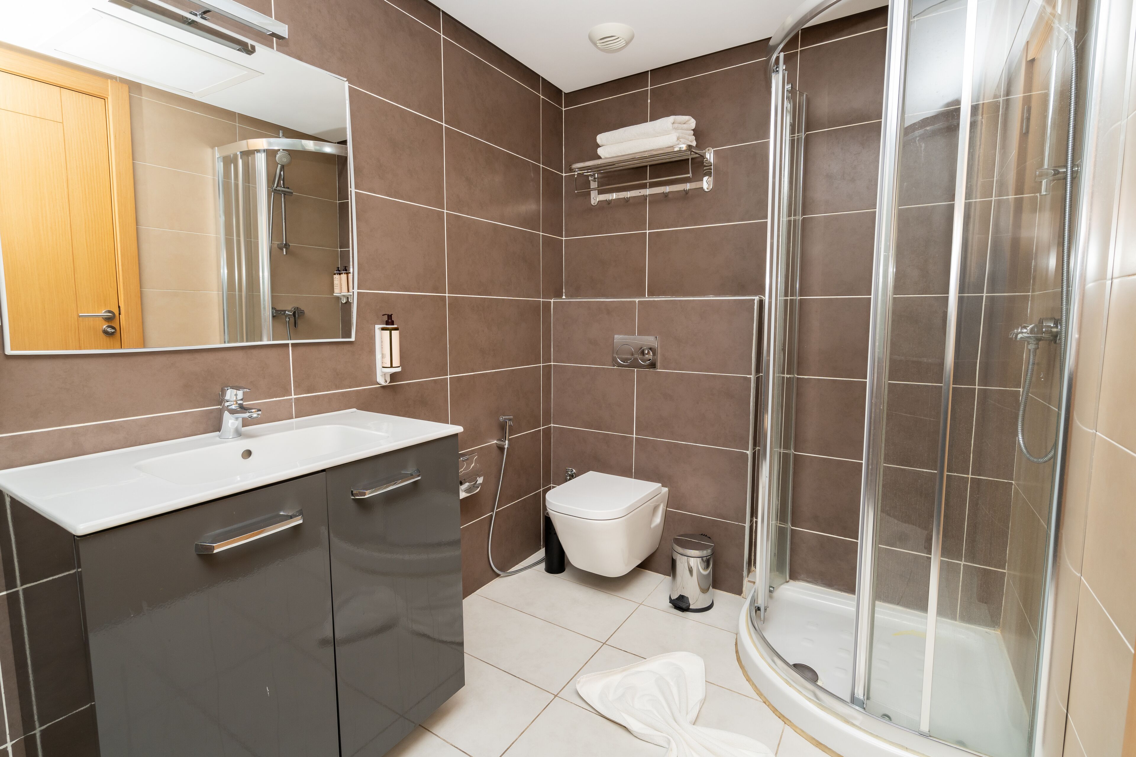 A modern bathroom with a shower, toilet, and sink.