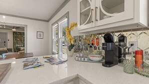 Una cucina moderna con mobili bianchi, una macchina da caffè e una pianta decorativa.