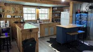 Eine rustikale Küche mit Holzausstattung, einer zentralen Kochinsel, einem Spülbecken und einem Kühlschrank.